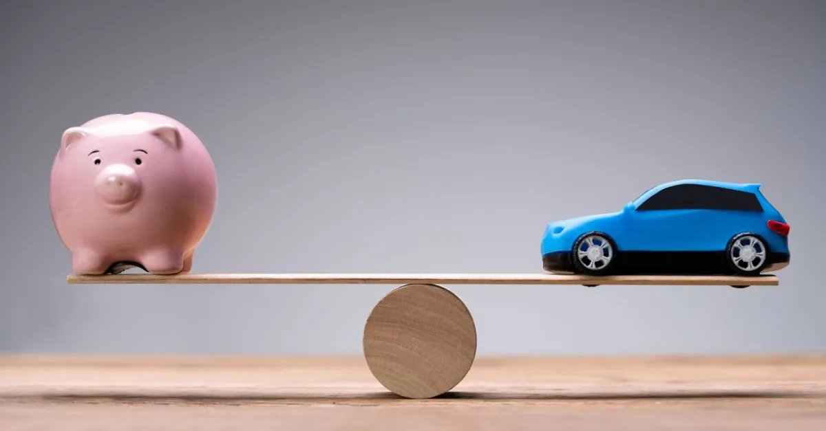 Ein Schaubild zeigt eine Holzwaage in Balance, mit einem Sparschwein auf der linken Waagschale und einem Spielzeugauto auf der rechten Seite, um die Kostenvergleiche zwischen Sparen und Autokauf zu symbolisieren.